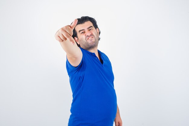 Homme mûr montrant le majeur en t-shirt bleu, à la grave, vue de face.