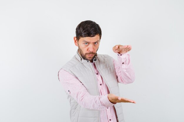 Homme mûr montrant le signe de la taille dans la chemise, la veste sans manches et l'air pensif. vue de face.