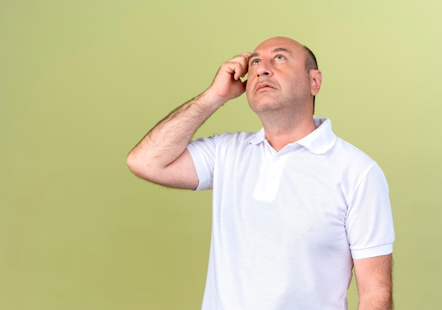 Homme mûr à la pensée jusqu'à la tête de gratter isolé sur fond vert olive