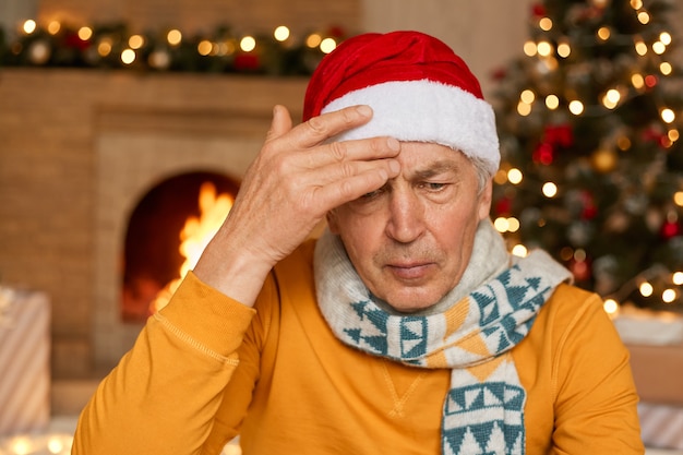 Homme mûr posant intérieur contre cheminée et sapin décoré