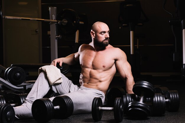 Homme musclé au milieu des haltères