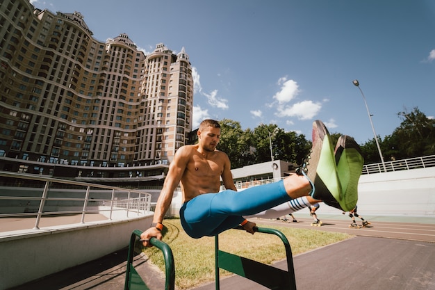 Photo gratuite homme musclé fort faisant des exercices sur des barres inégales dans une salle de sport de rue en plein air. concept de mode de vie d'entraînement.