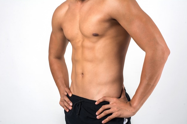 Homme musclé montrant six abs pack isolé sur fond blanc.