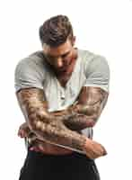 Photo gratuite homme musclé avec des tatouages se déshabillant. isolé sur blanc