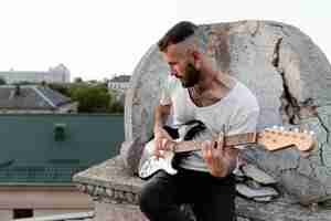 Photo gratuite homme musicien sur le toit à jouer de la guitare électrique