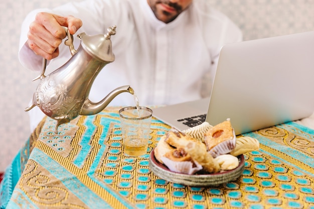 Homme musulman avec de la nourriture et un ordinateur portable