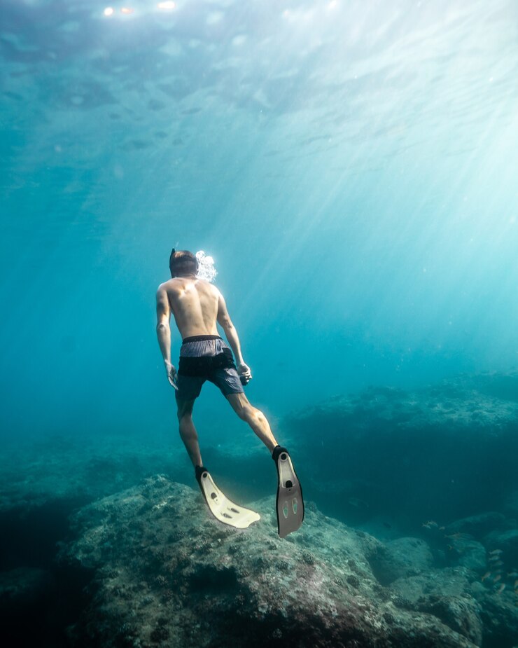 Photo gratuit un homme nageant sous l'eau par une journée ensoleillée.
