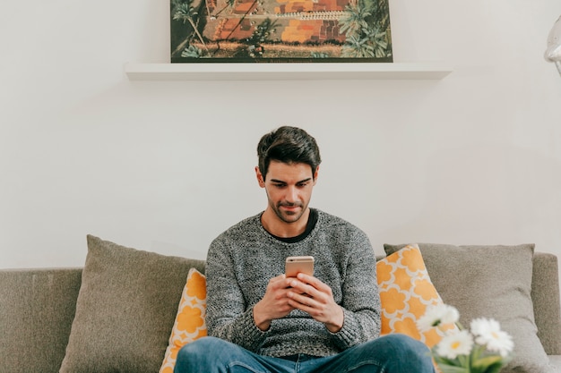 Homme naviguant sur smartphone dans le salon