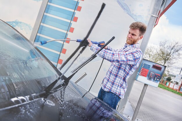 L'homme nettoie sa voiture dans un self-service