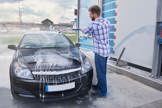 L'homme nettoie sa voiture dans un self-service