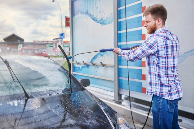 L'homme nettoie sa voiture dans un self-service