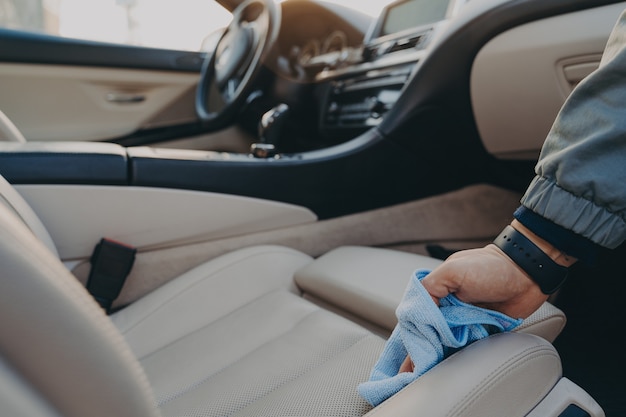 Homme nettoyant l'intérieur de la voiture avec un chiffon en microfibre au service de lavage de voiture