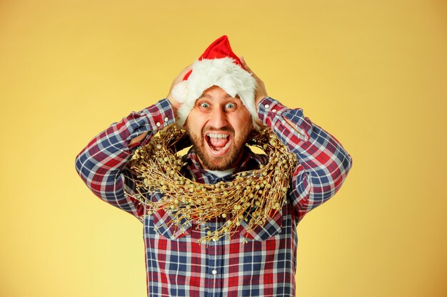 Homme de Noël souriant portant un bonnet de Noel sur le studio orange
