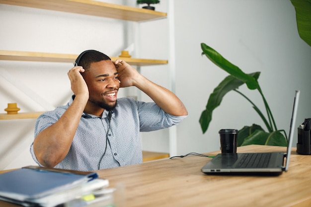 Homme noir assis au bureau portant des écouteurs et passer un appel vidéo