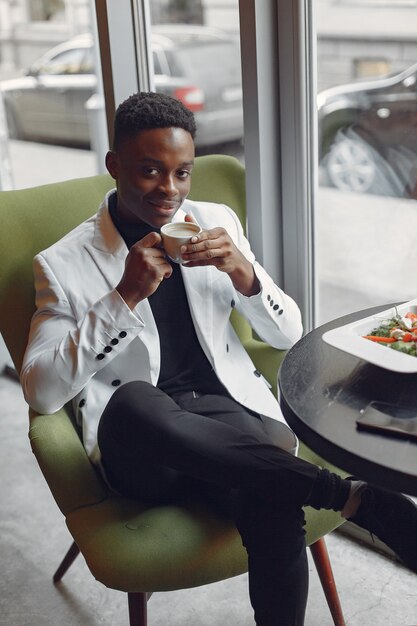 Homme noir assis dans un café et manger une salade de légumes