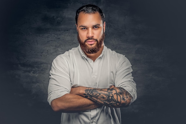 Photo gratuite homme noir barbu positif avec un tatouage sur les bras croisés, vêtu d'une chemise blanche.