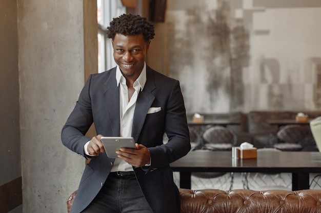 Homme noir dans un costume noir debout dans un café