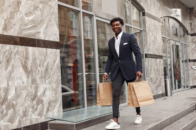 Homme noir élégant dans une ville avec des sacs à provisions