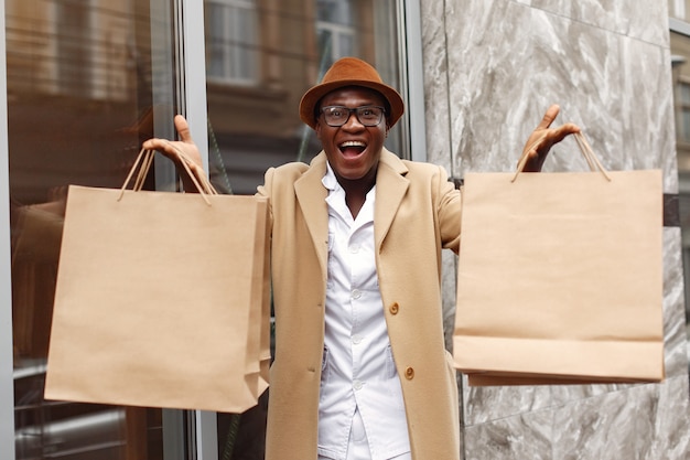 Photo gratuite homme noir élégant dans une ville avec des sacs à provisions