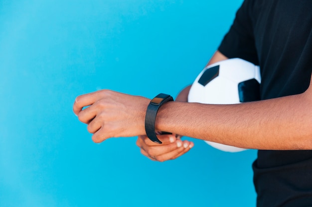 Homme noir avec le football fixant une montre intelligente