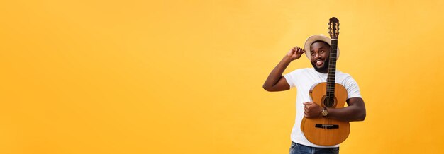 Photo gratuite homme noir musclé jouant de la guitare portant des jeans et débardeur blanc isoler sur fond jaune