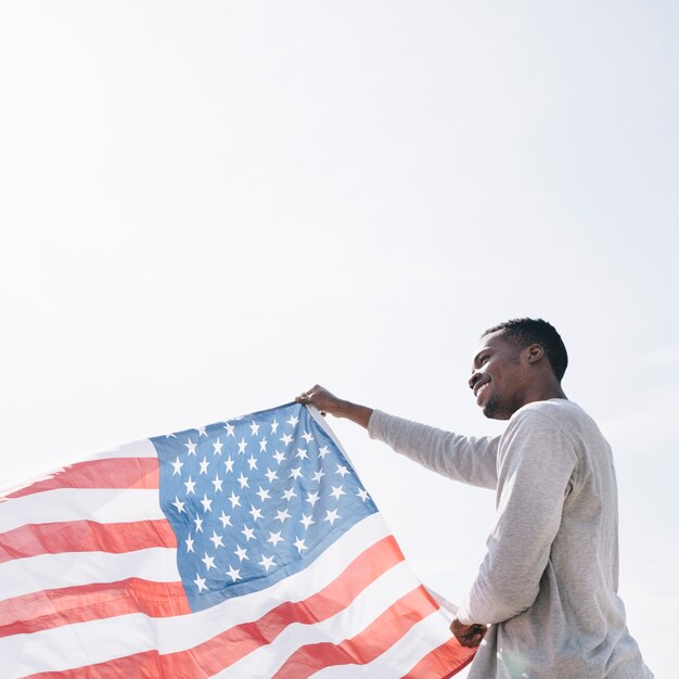 Homme noir souriant tenant agitant le drapeau américain sur le soleil