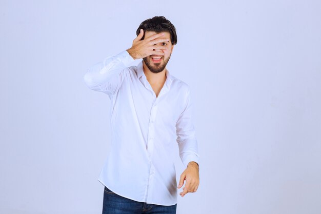 Homme observant l'extérieur à travers ses doigts ou cachant son visage.