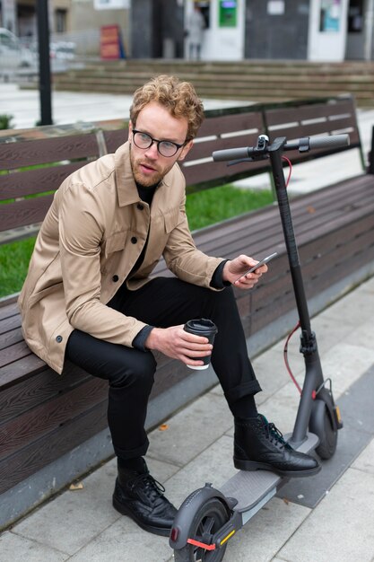 Homme occasionnel posant avec un scooter électrique