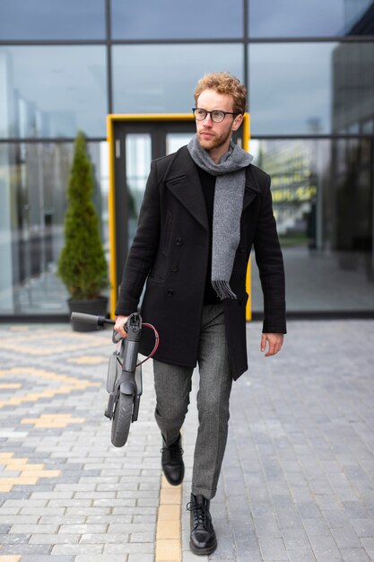 Homme occasionnel posant avec un scooter électrique