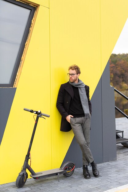 Homme occasionnel posant avec un scooter électrique