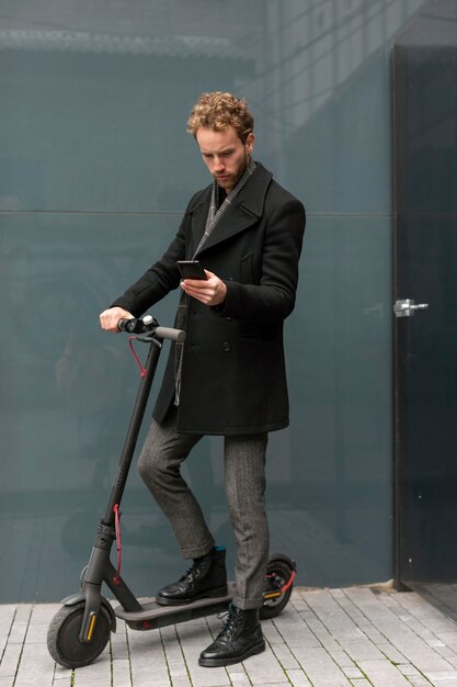 Homme occasionnel posant avec un scooter électrique