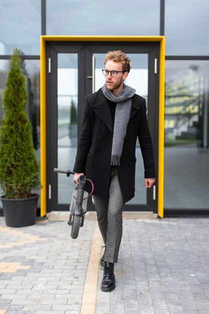 Homme occasionnel posant avec un scooter électrique