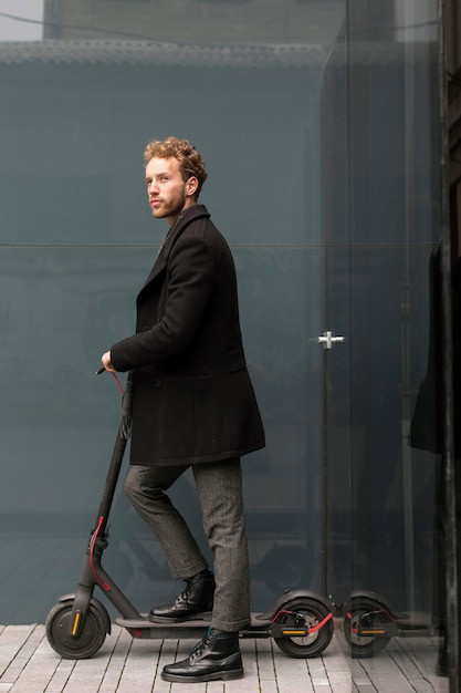 Photo gratuite homme occasionnel posant avec un scooter électrique