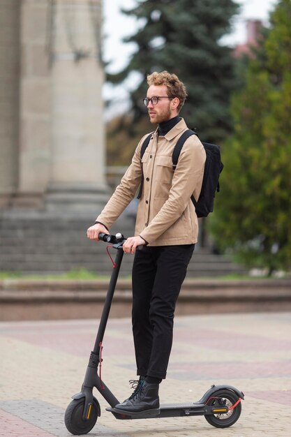 Homme occasionnel posant avec un scooter électrique