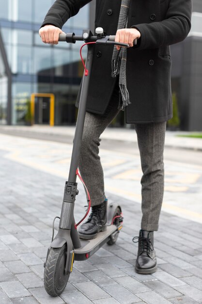 Homme occasionnel posant avec son scooter électrique