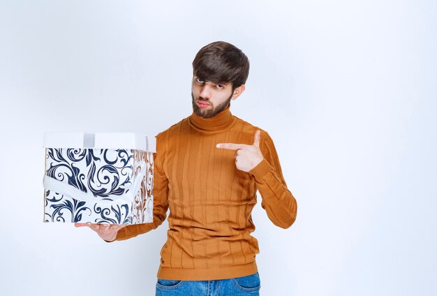 Homme offrant ou reçu un coffret cadeau blanc à motifs bleus.