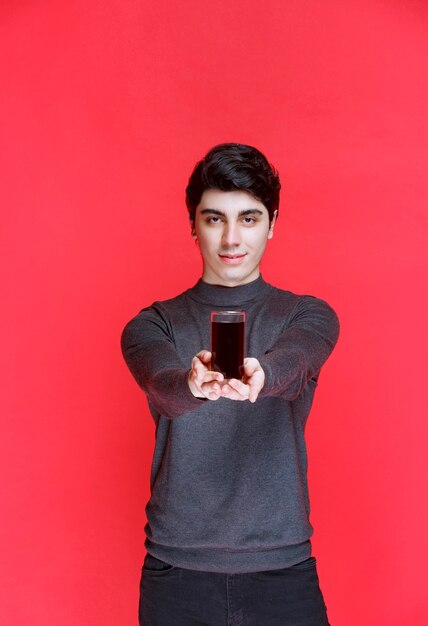 Homme offrant un verre de jus rouge