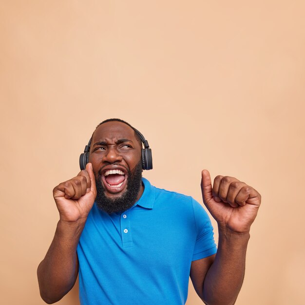 Un homme optimiste et joyeux à la peau foncée danse sans soucis et attrape chaque morceau de musique