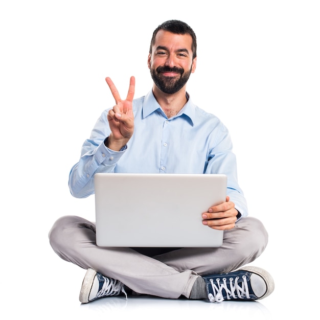 Homme avec un ordinateur portable faisant un geste de victoire