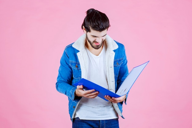 Homme ouvrant un dossier bleu et le vérifiant