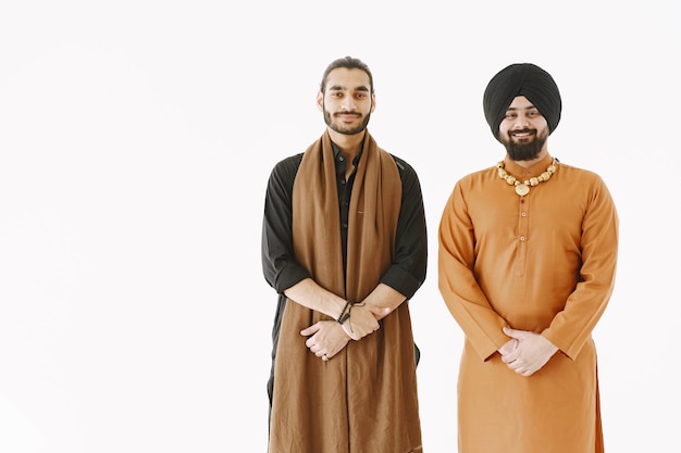 Homme pakistanais et hommes indiens en vêtements traditionnels. Les amis parlent sur fond blanc, isolés. Accord entre pays.