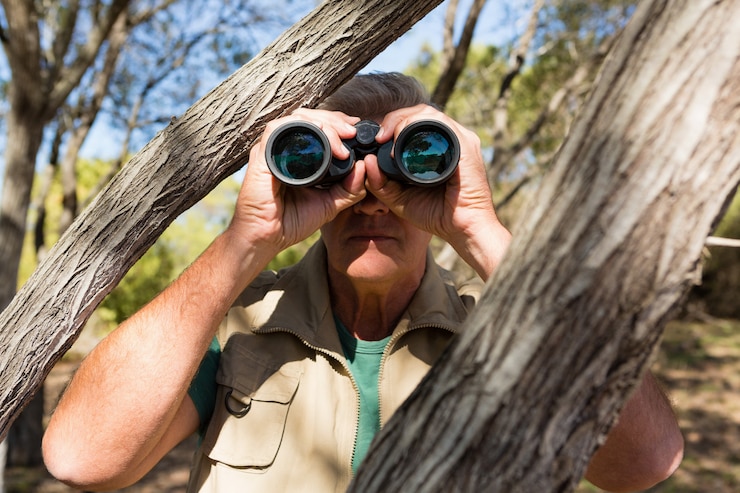 Photo gratuit homme par arbre regardant à travers des jumelles