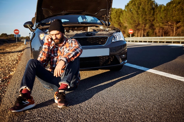 Homme parlant au téléphone à côté de la voiture