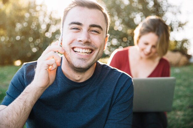 Homme parlant au téléphone près d&#39;une femme avec un ordinateur portable