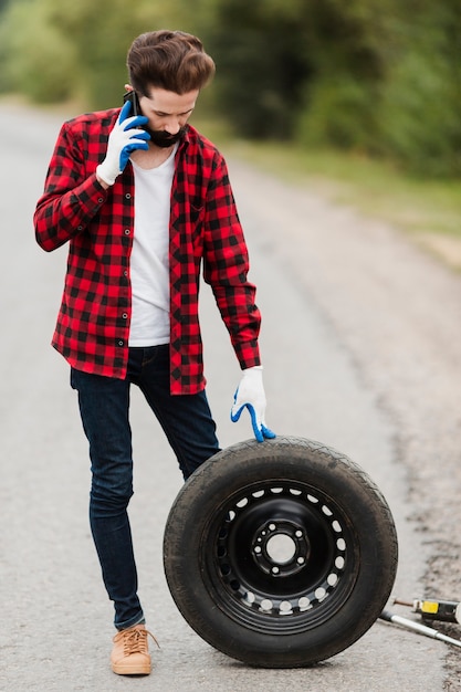 Homme parlant au téléphone et tenant un pneu