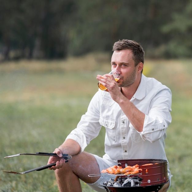 Photo gratuite homme participant au barbecue en plein air et boire de la bière