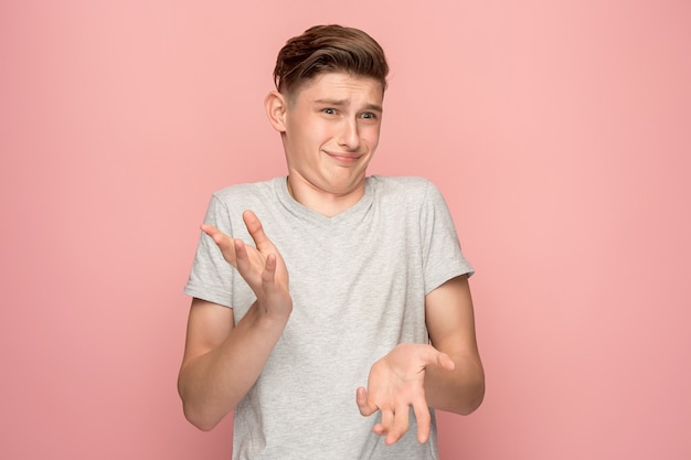 Homme pensif douteux avec une expression réfléchie faisant un choix contre le mur rose