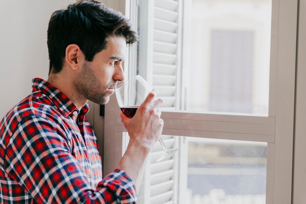 Homme pensif avec du vin à la fenêtre