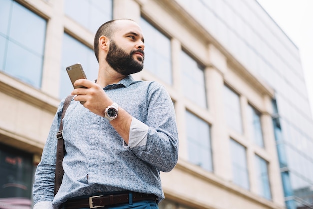 Homme pensif avec téléphone sur fond urbain