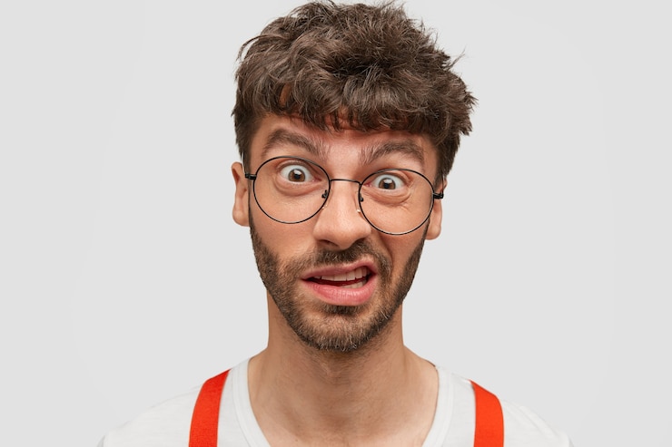 Photo gratuit homme perplexe frustré avec chaume sombre, fronce les sourcils face comme voit quelque chose de désagréable, isolé sur mur blanc